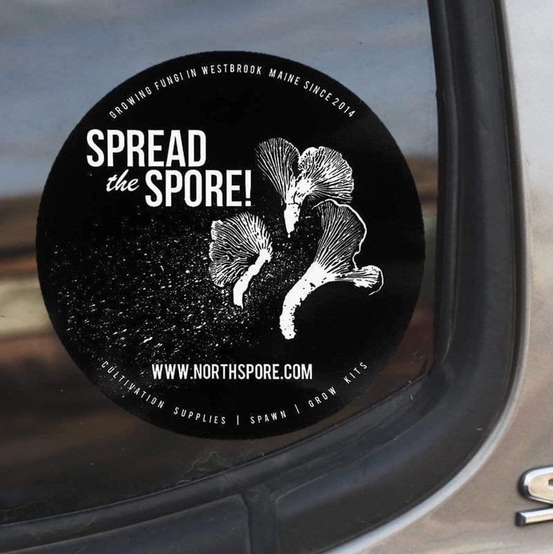 A black circle North Spore Spread the Spore sticker on the back windshield of a vehicle